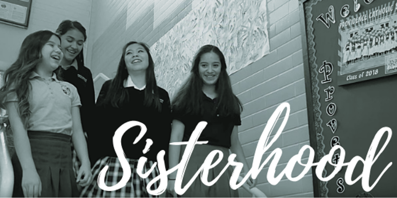 A group of girls are standing next to each other in front of a sign that says sisterhood.