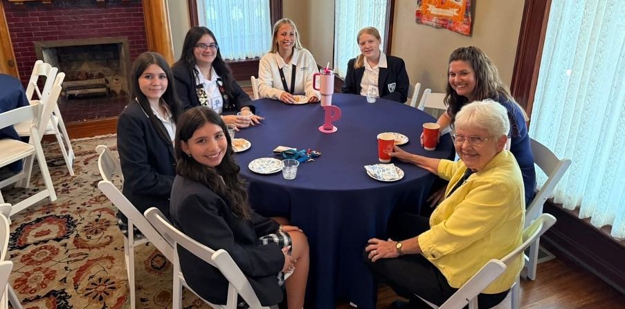 a group of girls in school uniforms are sitting around a table