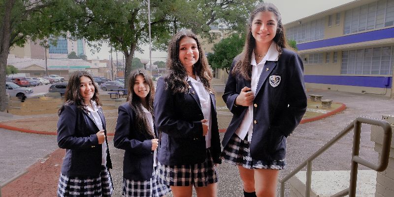 A group of girls in school uniforms are standing in front of a building.