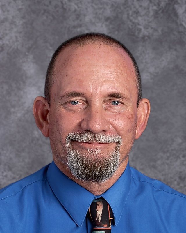 A man with a beard wearing a blue shirt and tie