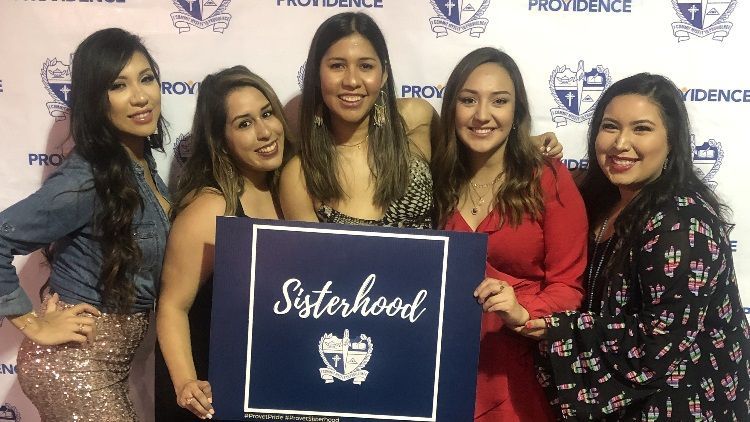 A group of women standing next to each other holding a sign that says sisterhood.