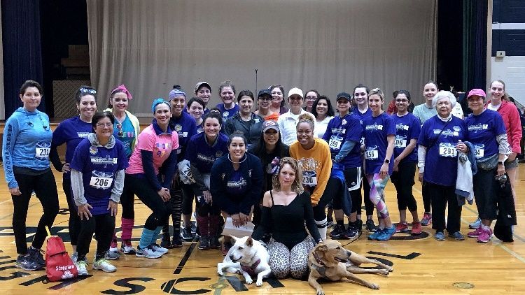 A large group of people are posing for a picture in a gym.