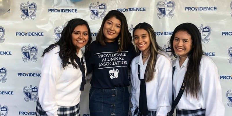 A group of young women are posing for a picture in front of a wall.