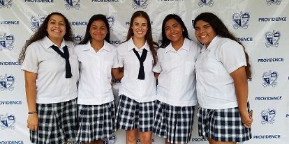 A group of girls in school uniforms are posing for a picture.