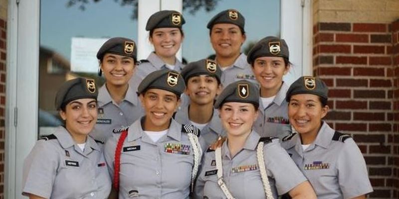 A group of soldiers are posing for a picture in front of a brick building.