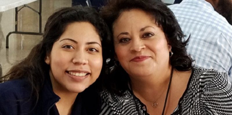 Two women are posing for a picture together and smiling for the camera.