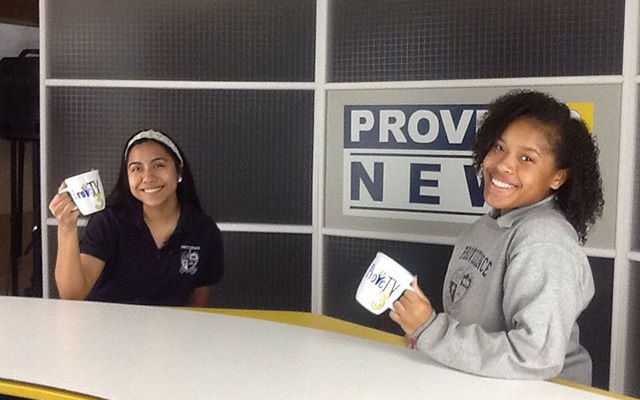 Two girls holding coffee mugs in front of a sign that says prov new