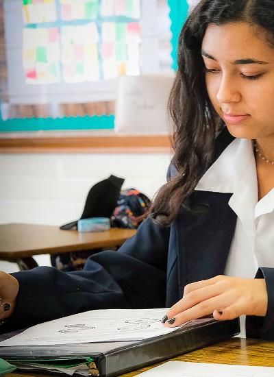 A girl is sitting at a desk in a classroom with her eyes closed