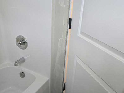 White bathtub and shower area with partially open white door.