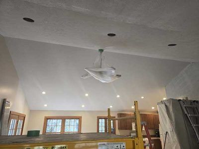 High ceilinged room with recessed lighting and a covered ceiling fan.