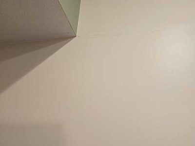 Off-white wall and ceiling corner; shadow on the left. Green paint on a small section of ceiling.