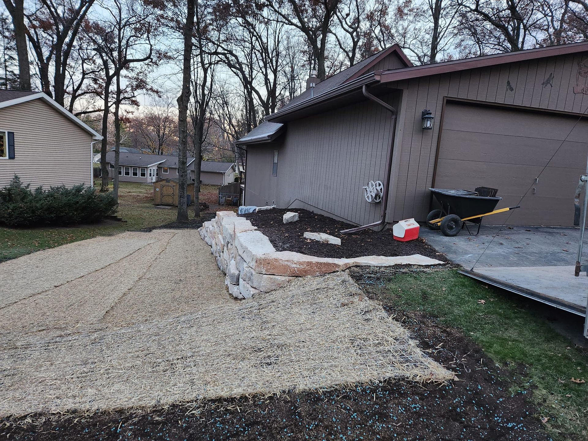 A gravel area next to a building, with a small retaining wall and a garage.