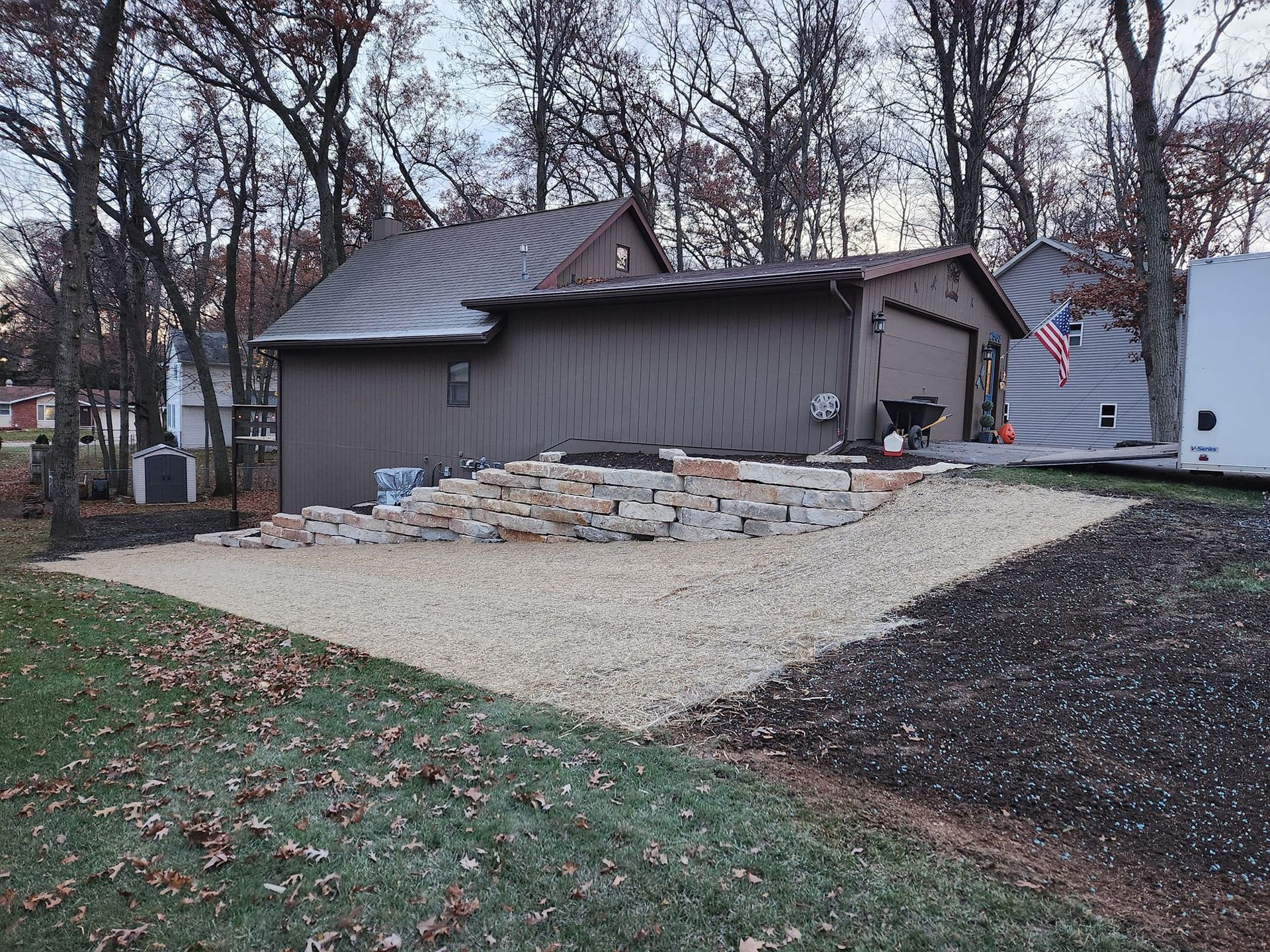 Gravel and brick patio next to a brown building. A pile of bricks sits on the patio.