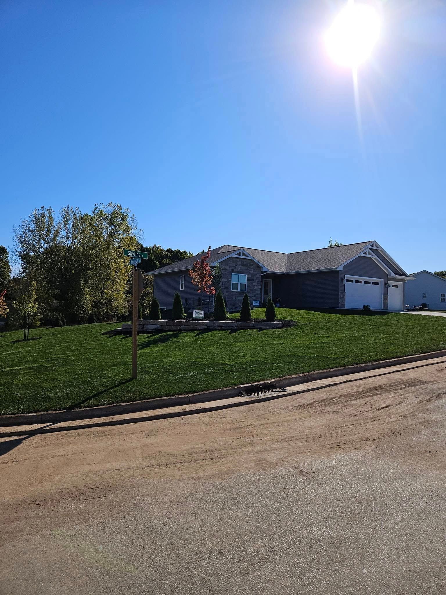 A one-story house with a green lawn under a bright sun.