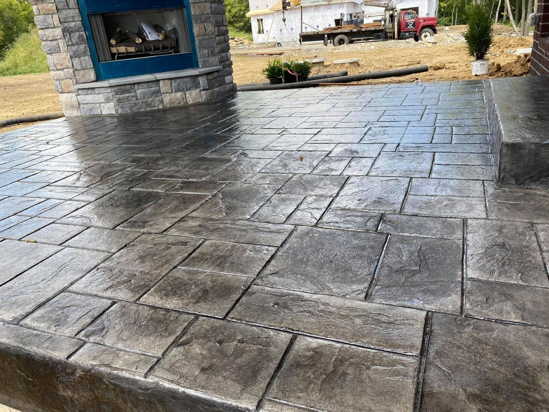 Stained concrete patio with a stone fireplace and textured block pattern.