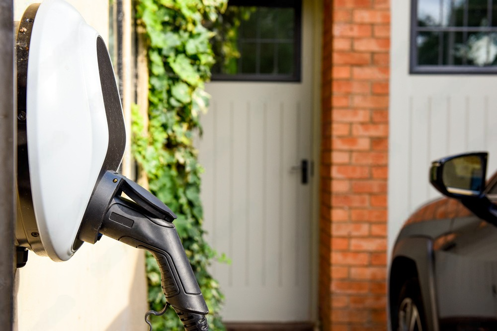 a car is being charged at a charging station outside of a house .