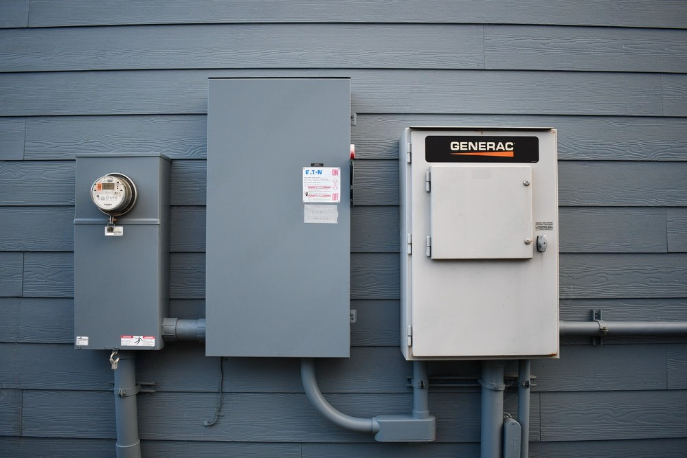 a gray and white electrical box on the side of a building .