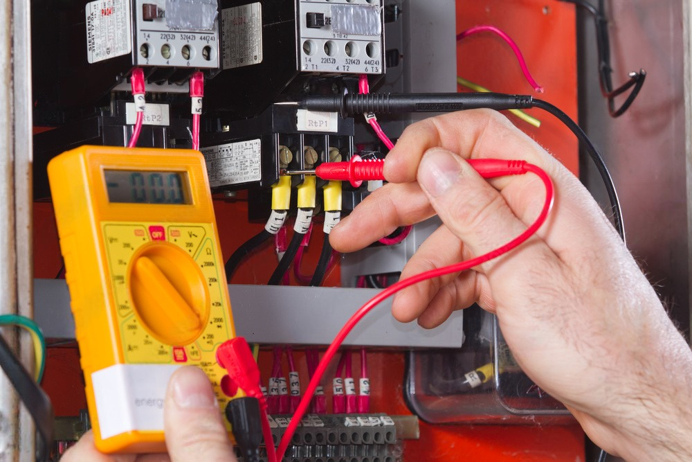 a person is using a digital multimeter to test a circuit board .