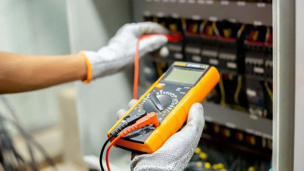 a person is using a multimeter to test a circuit board .