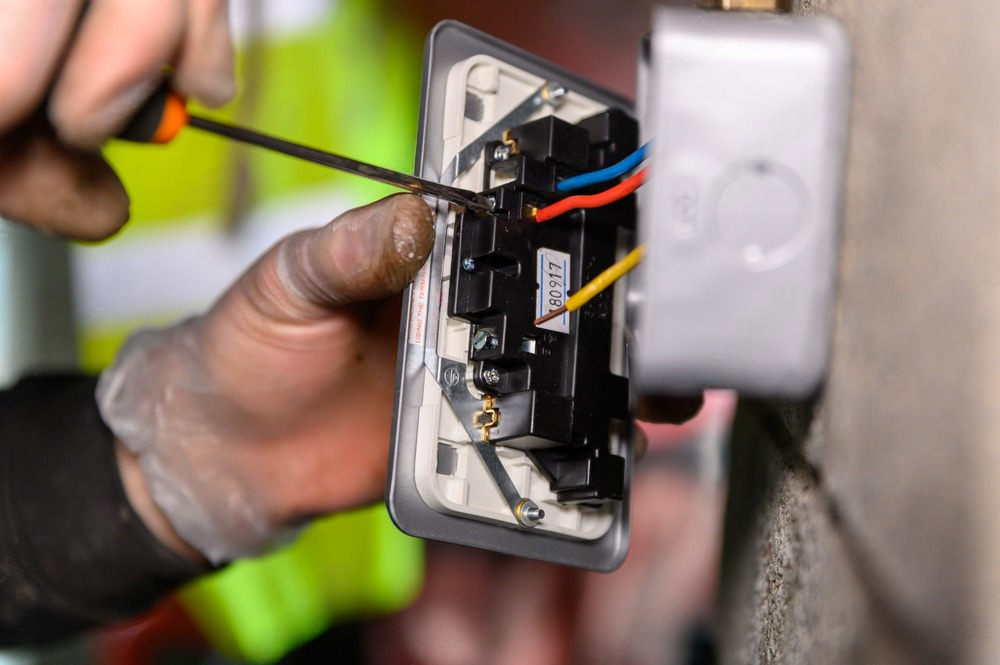 a man is fixing a light switch with a screwdriver .