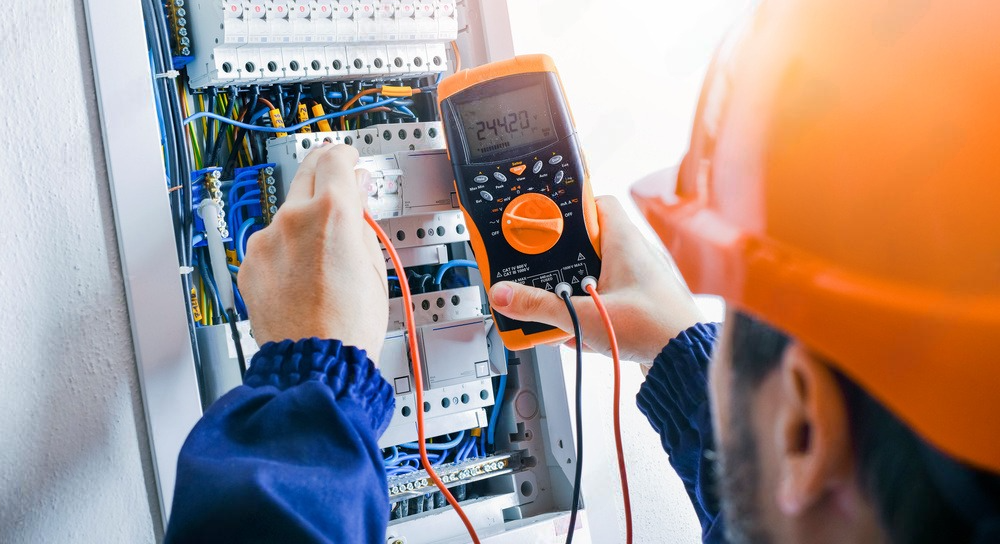 an electrician is using a multimeter to test an electrical box .