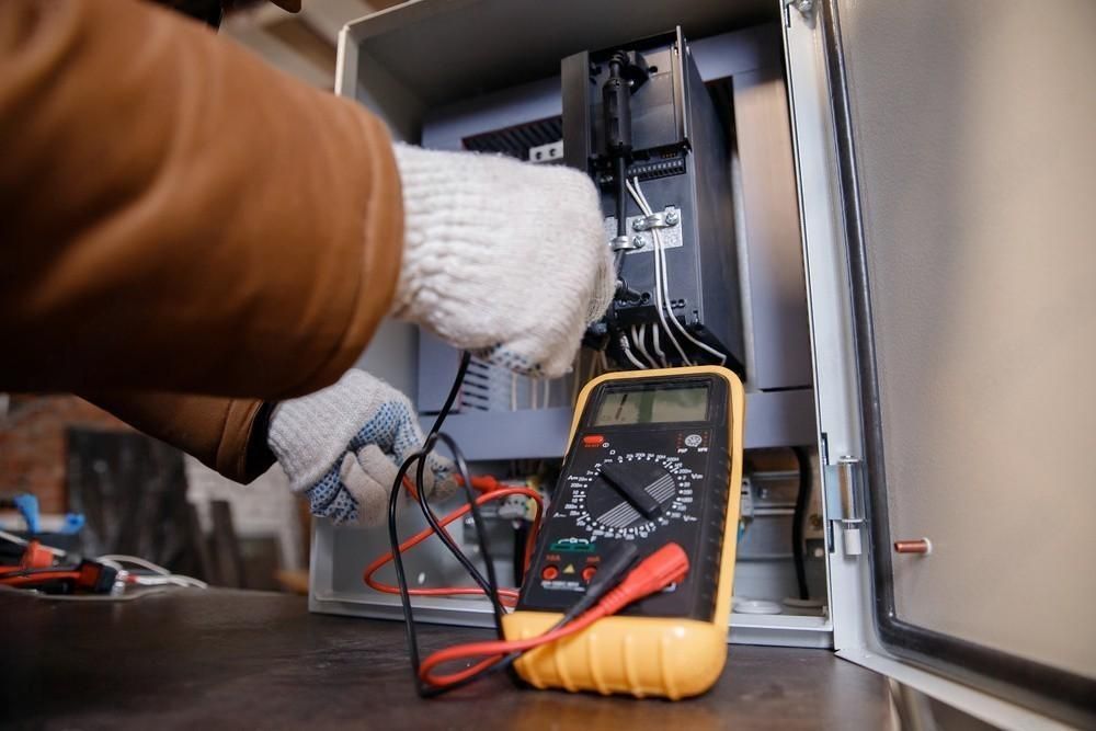 a person is using a multimeter to test an electrical box .