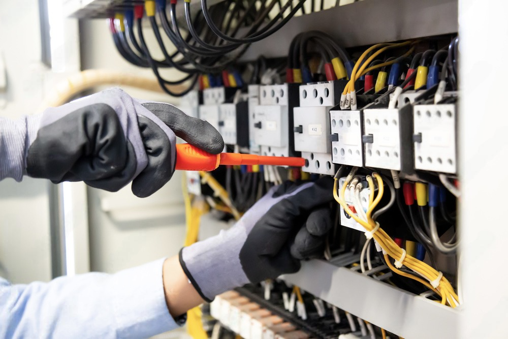 an electrician is working on an electrical box with a wrench .