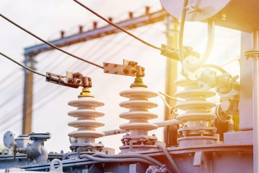 a close up of a power transformer with the sun shining through the wires .