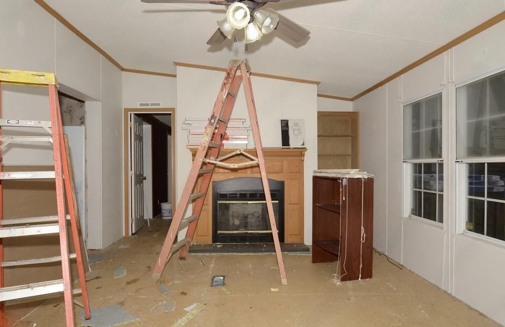 an empty living room with a ladder and a ceiling fan