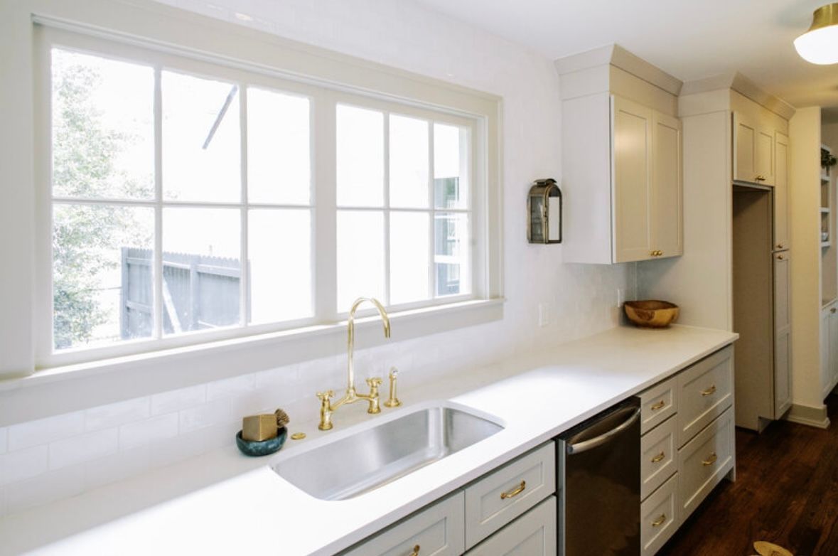 A kitchen with a sink , dishwasher , and large window.
