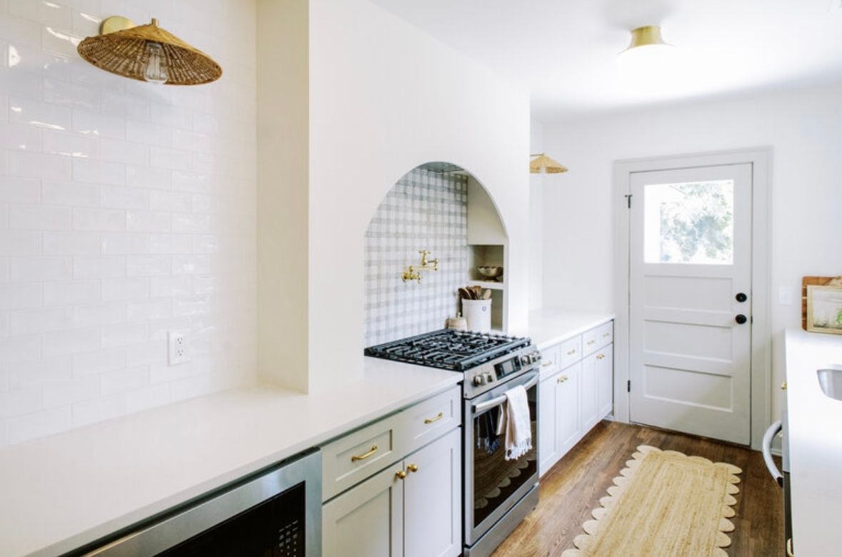 A kitchen with white cabinets and a stove top oven