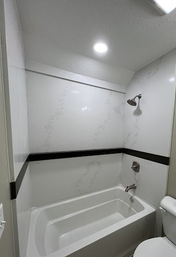 A bathroom with a bathtub , toilet and shower.
