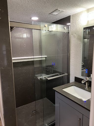 A bathroom with a sink and a walk in shower.