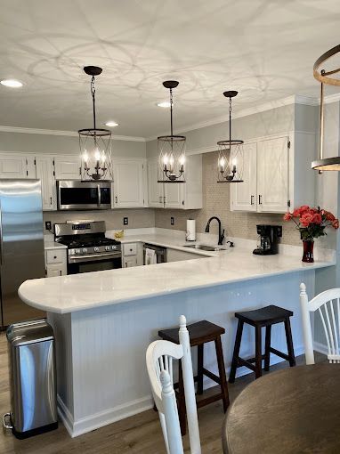 A kitchen with white cabinets , stainless steel appliances , a table and chairs.