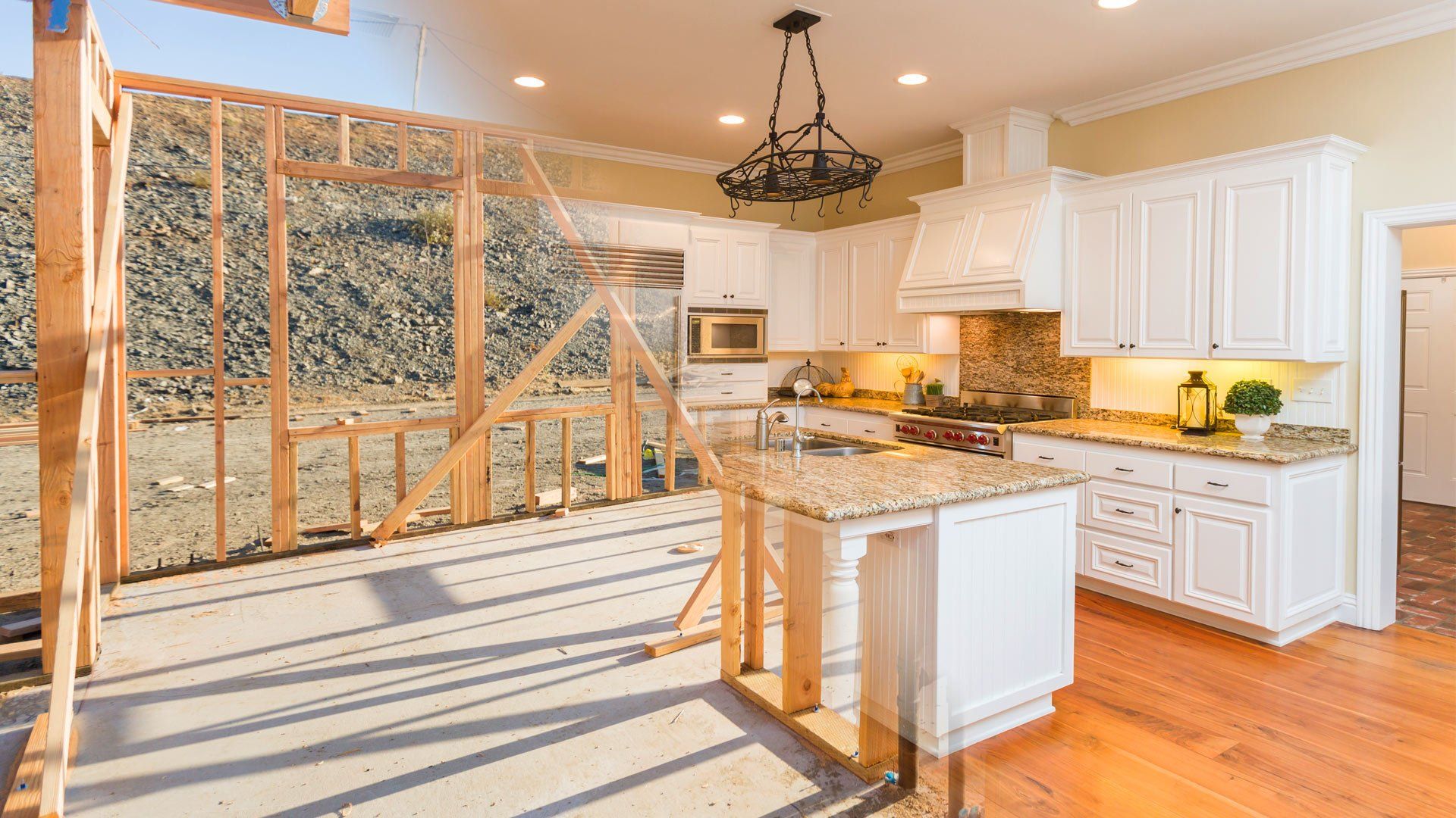 A kitchen in a house under construction with white cabinets and granite counter tops.