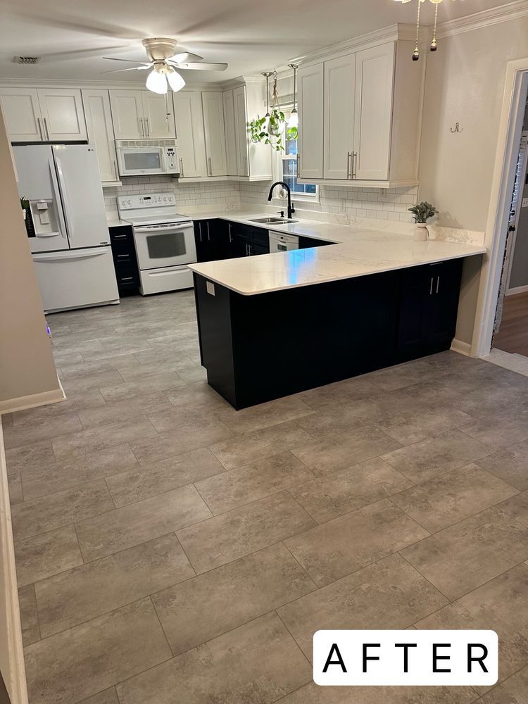 A kitchen with black cabinets , white counter tops , and a large island.