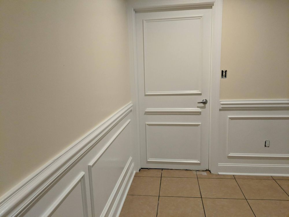 A hallway with white trim and a white door