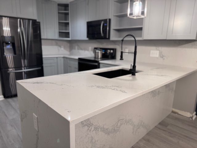 A kitchen with white counter tops and black appliances
