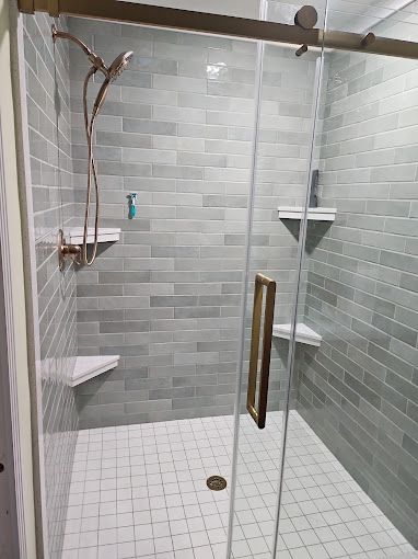 A shower with a sliding glass door and a shower head.