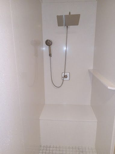 A shower with a bench and a shower head in a bathroom.