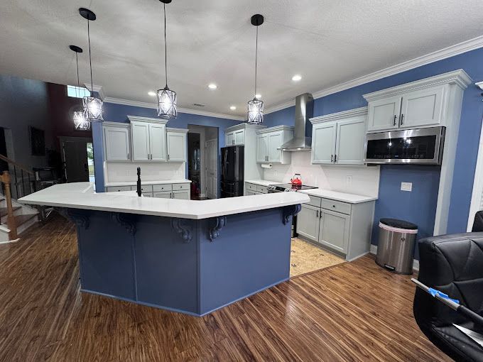 A kitchen with blue walls and white cabinets and a large island.