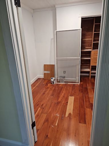 A room with hardwood floors and a television in a closet.