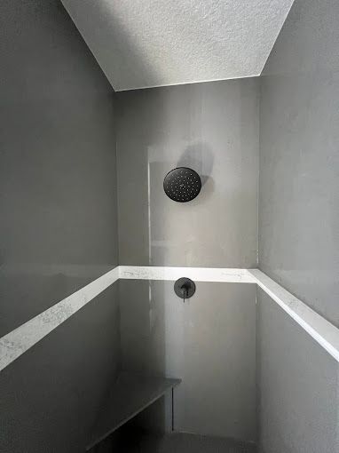 A bathroom with a shower head and a bench.