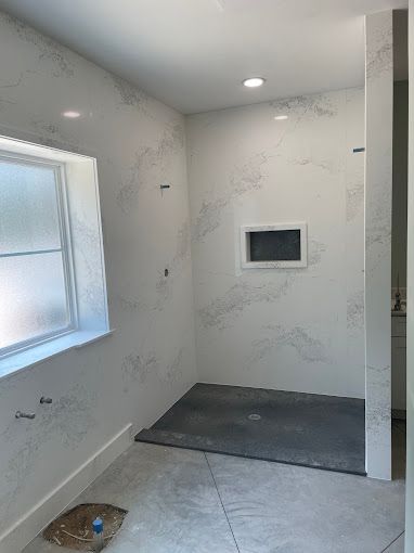 A bathroom with a walk in shower and a window.