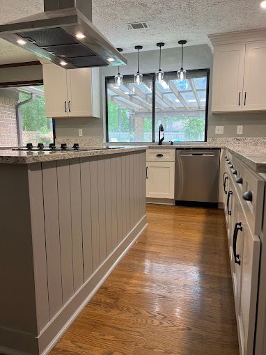 A kitchen with white cabinets , stainless steel appliances , and hardwood floors.