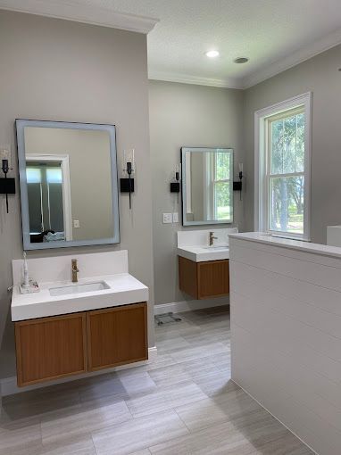 A bathroom with two sinks , a mirror and two windows.