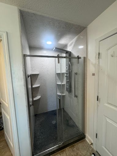 A bathroom with a sliding glass shower door and a shower head.