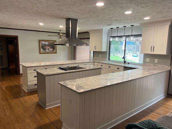 A kitchen with white cabinets and granite counter tops.