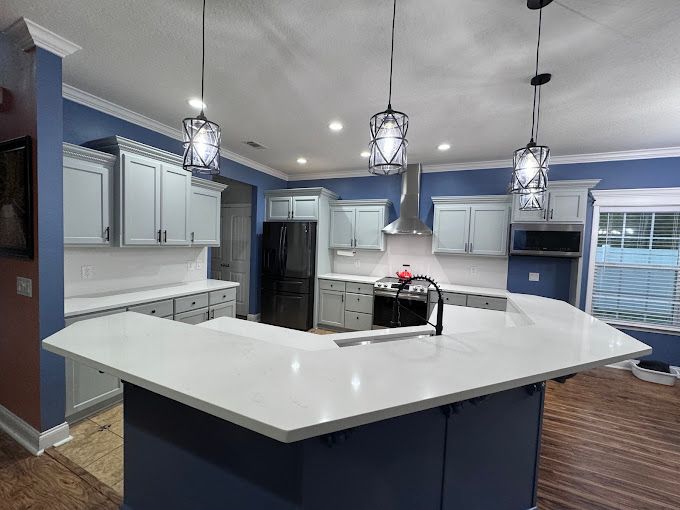 A kitchen with blue cabinets and white counter tops and a large island.