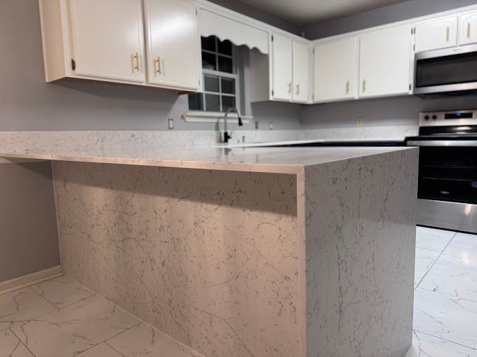 A kitchen with white cabinets and a large island in the middle.